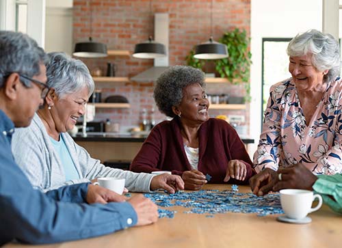 Group of elderly people working on a jigsaw puzzle at a table.